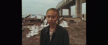 Movie still from “Ritual” (2000), directed by Hideaki Anno – A woman standing in front of an overpass; Medium shot, High angle
