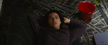 Movie still from “Ritual” (2000), directed by Hideaki Anno – A man laying on the ground with his hands behind his head; Medium shot, Overhead angle