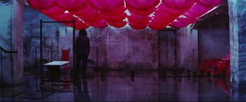 Movie still from “Ritual” (2000), directed by Hideaki Anno – A person standing in front of a wall with a bunch of pink umbrellas; Wide shot, High angle