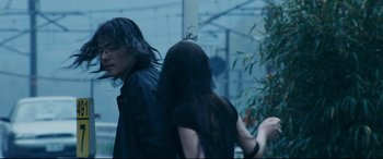 Movie still from “Ritual” (2000), directed by Hideaki Anno – A man and a woman walking down a street; Medium shot, Over the shoulder angle