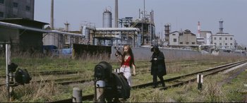 Movie still from “Ritual” (2000), directed by Hideaki Anno – A woman holding a gun while standing next to another woman; Wide shot, Low angle