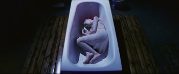 Movie still from “Ritual” (2000), directed by Hideaki Anno – A woman laying in a bath tub on the ground; Wide shot, Overhead angle