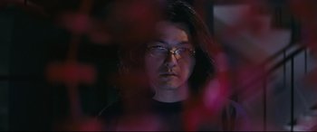 Movie still from “Ritual” (2000), directed by Hideaki Anno – A man with glasses is looking at the camera; Close Up shot, Low angle