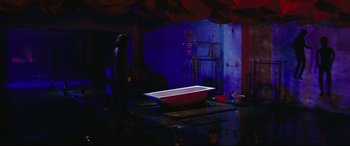 Movie still from “Ritual” (2000), directed by Hideaki Anno – A woman standing in front of a bathtub in a dark room; Wide shot, High angle