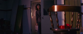 Movie still from “Ritual” (2000), directed by Hideaki Anno – A woman standing in a doorway holding a laptop; Medium shot, Low angle