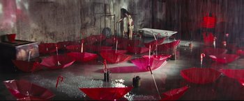 Movie still from “Ritual” (2000), directed by Hideaki Anno – A woman standing in the middle of a room with red umbrellas; Extreme Wide shot, Overhead angle