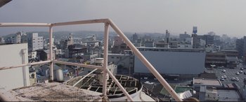 Movie still from “Ritual” (2000), directed by Hideaki Anno – A view of a city from a roof top; Extreme Wide shot, Low angle