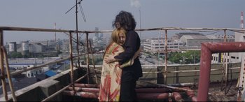 Movie still from “Ritual” (2000), directed by Hideaki Anno – A man and a woman hugging on top of a building; Medium shot, Low angle