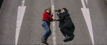 Movie still from “Ritual” (2000), directed by Hideaki Anno – A man and a woman laying in the street; Wide shot, Overhead angle