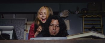 Movie still from “Ritual” (2000), directed by Hideaki Anno – A woman and a man sitting in front of a computer; Medium shot, Low angle