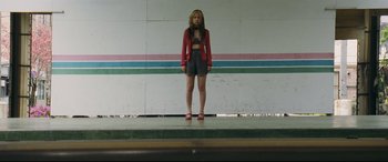 Movie still from “Ritual” (2000), directed by Hideaki Anno – A woman standing on a stage wearing shorts and a jacket; Wide shot, Low angle