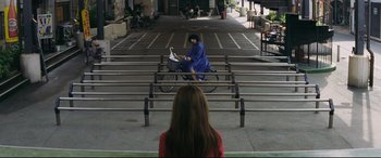 Movie still from “Ritual” (2000), directed by Hideaki Anno – A person on a bike in front of a woman; Extreme Wide shot, High angle