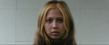 Movie still from “Ritual” (2000), directed by Hideaki Anno – A woman with long blonde hair wearing a black shirt; Close Up shot, Low angle