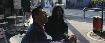Movie still from “Ritual” (2000), directed by Hideaki Anno – Two men sitting on the side of the street; Medium shot, Low angle