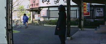 Movie still from “Ritual” (2000), directed by Hideaki Anno – A woman standing on the side of the street; Wide shot, Low angle