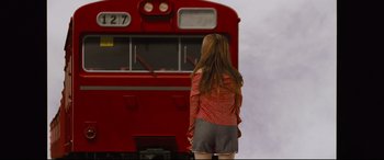 Movie still from “Ritual” (2000), directed by Hideaki Anno – A woman standing in front of a red train; Wide shot, Low angle
