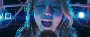 Movie still from “Ritual” (2000), directed by Hideaki Anno – A young girl is singing into a microphone; Close Up shot, Overhead angle
