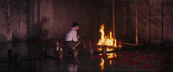 Movie still from “Ritual” (2000), directed by Hideaki Anno – A man kneeling in front of a fire pit; Wide shot, High angle