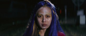 Movie still from “Ritual” (2000), directed by Hideaki Anno – A woman with blue and yellow hair is posing for a picture; Close Up shot, Low angle