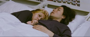 Movie still from “Ritual” (2000), directed by Hideaki Anno – A man and a woman laying in a bed together; Medium shot, Overhead angle