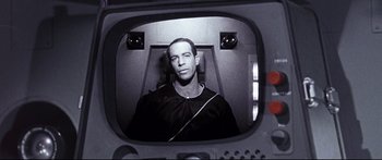 Movie still from “Robinson Crusoe on Mars” (1964), directed by Byron Haskin – A black and white photo of a man sitting in front of a television; Close Up shot, Over the shoulder angle