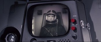 Movie still from “Robinson Crusoe on Mars” (1964), directed by Byron Haskin – A man wearing a space suit and a helmet is seen through a television screen; Close Up shot, Over the shoulder angle