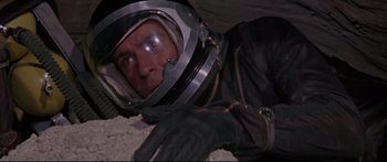 Movie still from “Robinson Crusoe on Mars” (1964), directed by Byron Haskin – A man in a space suit laying on the ground; Medium shot, Overhead angle