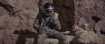 Movie still from “Robinson Crusoe on Mars” (1964), directed by Byron Haskin – A man in a space suit sitting on the ground; Medium shot, Overhead angle