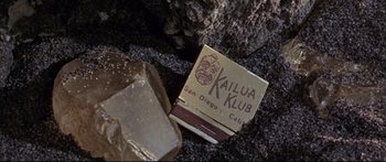 Movie still from “Robinson Crusoe on Mars” (1964), directed by Byron Haskin – An open cigarette packet sitting next to a piece of chocolate; Extreme Close Up shot, Overhead angle