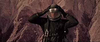 Movie still from “Robinson Crusoe on Mars” (1964), directed by Byron Haskin – A man in a spacesuit is putting on a helmet; Medium shot, Low angle