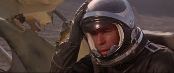 Movie still from “Robinson Crusoe on Mars” (1964), directed by Byron Haskin – A man wearing a helmet while holding an umbrella; Close Up shot, Overhead angle