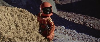 Movie still from “Robinson Crusoe on Mars” (1964), directed by Byron Haskin – A dog dressed in a space suit sitting on top of a rock; Wide shot, Low angle