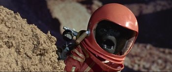 Movie still from “Robinson Crusoe on Mars” (1964), directed by Byron Haskin – A monkey in a red suit and helmet; Close Up shot, Low angle