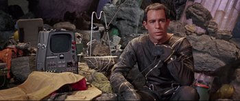 Movie still from “Robinson Crusoe on Mars” (1964), directed by Byron Haskin – A man sitting on the ground in front of rocks; Medium shot, High angle