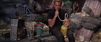 Movie still from “Robinson Crusoe on Mars” (1964), directed by Byron Haskin – A man sitting on the ground holding a fire extinguisher; Medium shot, High angle