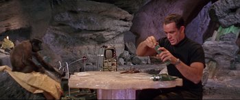 Movie still from “Robinson Crusoe on Mars” (1964), directed by Byron Haskin – A man sitting at a table in front of an old tv; Medium shot, Low angle