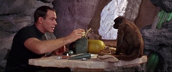 Movie still from “Robinson Crusoe on Mars” (1964), directed by Byron Haskin – A man sitting at a table with an object in front of him; Medium shot, Low angle