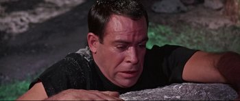 Movie still from “Robinson Crusoe on Mars” (1964), directed by Byron Haskin – A person laying on the ground near some rocks; Close Up shot, High angle