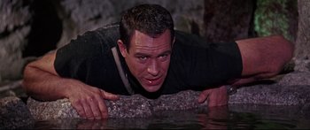 Movie still from “Robinson Crusoe on Mars” (1964), directed by Byron Haskin – A man in a black shirt is laying on the ground; Close Up shot, High angle