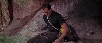 Movie still from “Robinson Crusoe on Mars” (1964), directed by Byron Haskin – A man sitting on the side of a rock wall; Medium shot, High angle