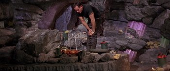 Movie still from “Robinson Crusoe on Mars” (1964), directed by Byron Haskin – A man standing over a fire in a cave; Medium shot, Low angle