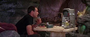 Movie still from “Robinson Crusoe on Mars” (1964), directed by Byron Haskin – A man sitting in front of a computer eating food; Medium shot, Over the shoulder angle