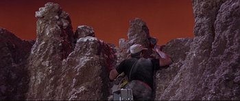 Movie still from “Robinson Crusoe on Mars” (1964), directed by Byron Haskin – A man is climbing up a rock formation; Wide shot, Low angle