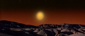 Movie still from “Robinson Crusoe on Mars” (1964), directed by Byron Haskin – A full moon setting in the sky over a rocky area; Extreme Wide shot, Low angle