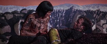 Movie still from “Robinson Crusoe on Mars” (1964), directed by Byron Haskin – A man is sitting on the ground with a fire hydrant in front of him; Medium shot, Overhead angle