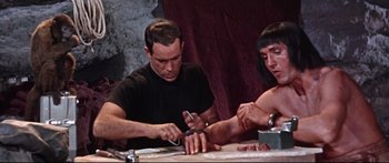 Movie still from “Robinson Crusoe on Mars” (1964), directed by Byron Haskin – A man and a woman are cutting meat together; Medium shot, Low angle
