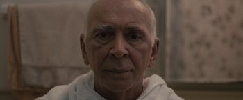 Movie still from “Robot & Frank” (2012), directed by Jake Schreier – An older man with a shaved head is looking at the camera; Close Up shot, Over the shoulder angle