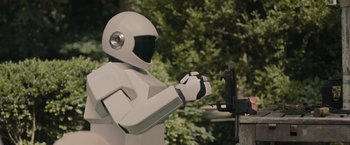 Movie still from “Robot & Frank” (2012), directed by Jake Schreier – A person in a white suit is cutting a piece of wood; Medium shot, Low angle