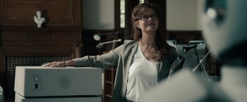 Movie still from “Robot & Frank” (2012), directed by Jake Schreier – A woman with glasses is standing in front of a podium; Medium shot, Over the shoulder angle