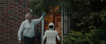 Movie still from “Robot & Frank” (2012), directed by Jake Schreier – A man standing in front of a white robot statue; Medium shot, Over the shoulder angle